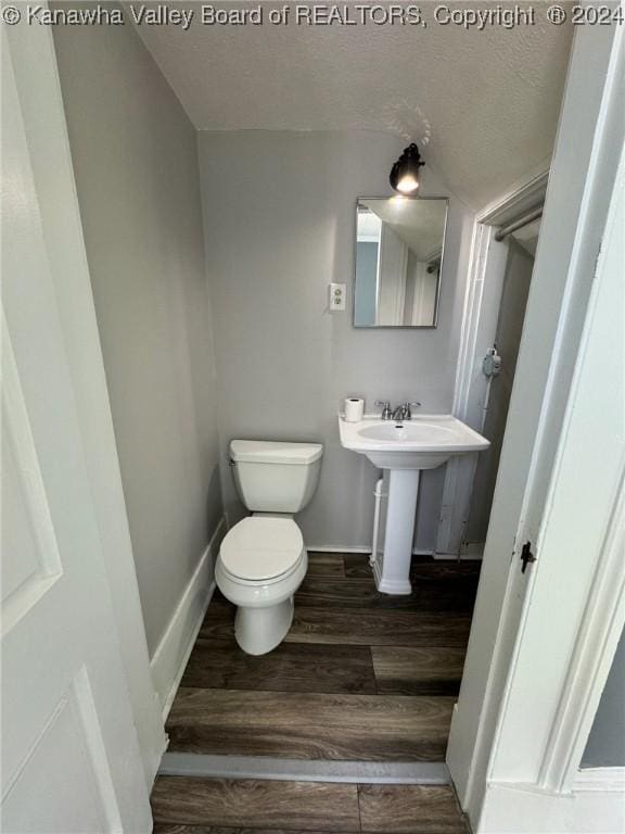 bathroom with wood-type flooring, a textured ceiling, toilet, and sink