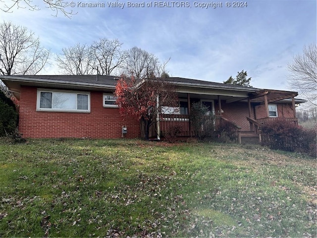 rear view of house featuring a lawn and covered porch