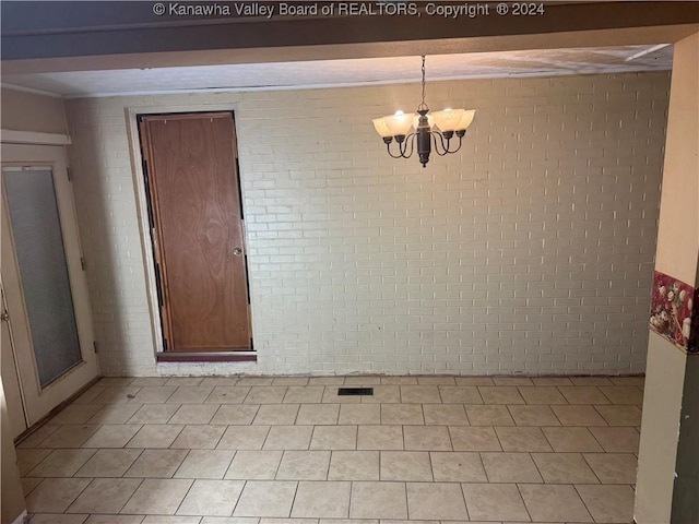 unfurnished dining area featuring brick wall and a notable chandelier