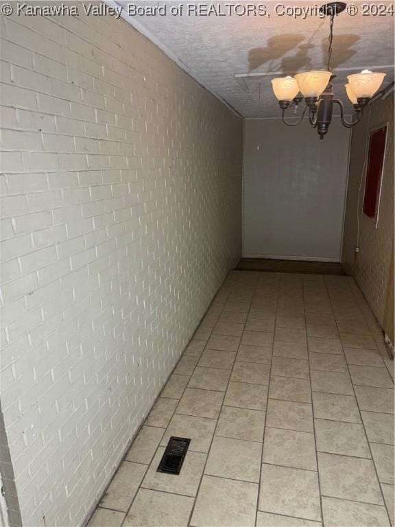 hallway with light tile patterned floors and an inviting chandelier