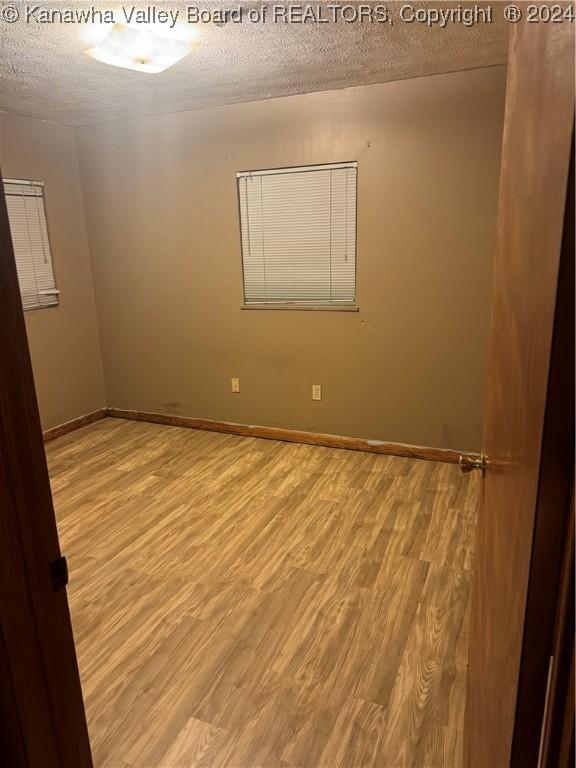 unfurnished room with light hardwood / wood-style floors and a textured ceiling