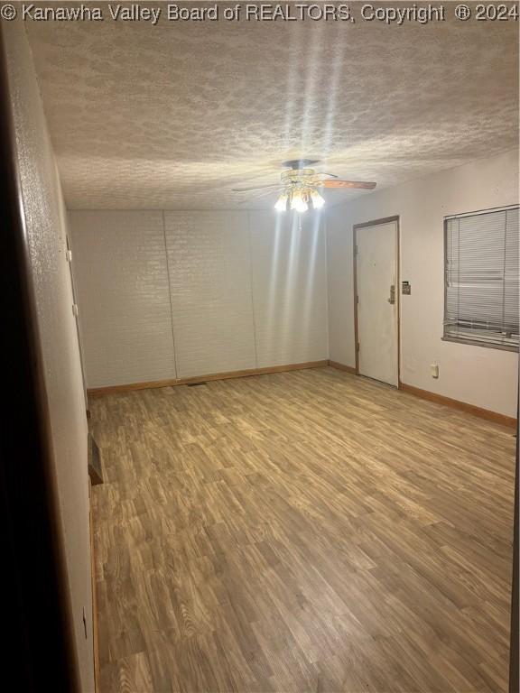 unfurnished room with ceiling fan, light hardwood / wood-style floors, and a textured ceiling