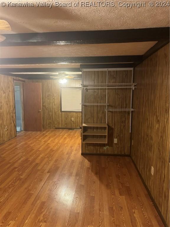 basement featuring hardwood / wood-style flooring, a textured ceiling, and wooden walls