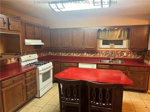 kitchen featuring a textured ceiling, white appliances, sink, and light tile patterned floors