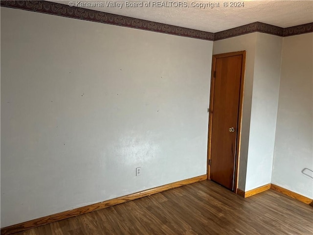 empty room featuring dark wood-type flooring and a textured ceiling