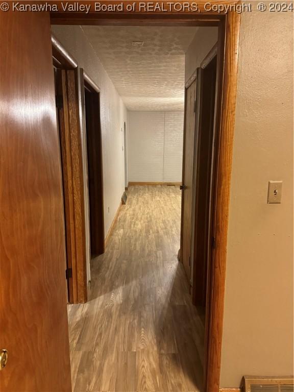 corridor with hardwood / wood-style floors and a textured ceiling