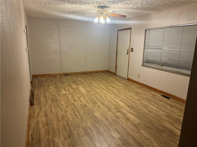 spare room featuring ceiling fan, light hardwood / wood-style flooring, and a textured ceiling