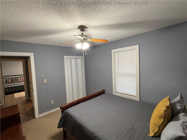 bedroom featuring dark colored carpet, a textured ceiling, and ceiling fan