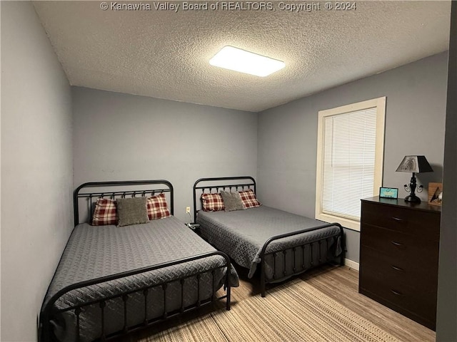 bedroom with light hardwood / wood-style flooring and a textured ceiling