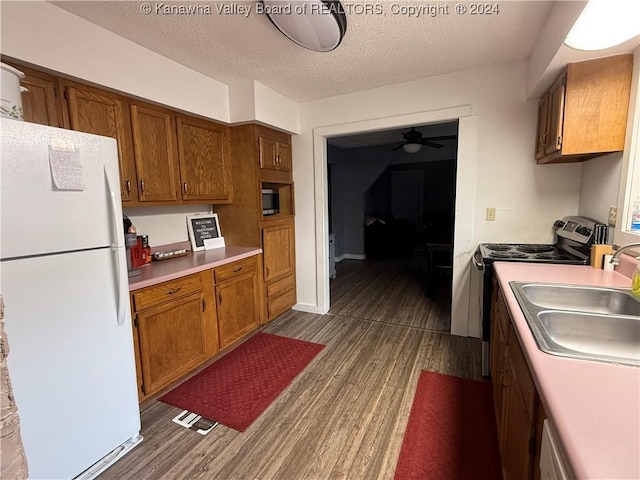 kitchen featuring dark hardwood / wood-style flooring, a textured ceiling, stainless steel electric stove, sink, and white fridge