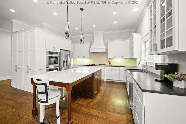 kitchen featuring appliances with stainless steel finishes, custom exhaust hood, dark wood-type flooring, white cabinets, and a kitchen island