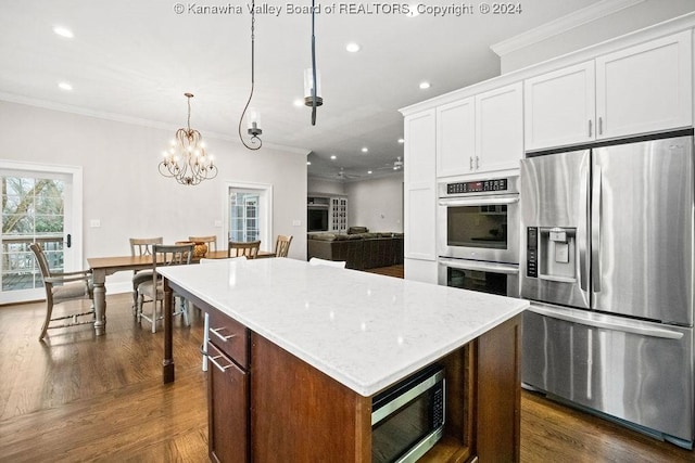 kitchen featuring stainless steel appliances, crown molding, pendant lighting, white cabinets, and a kitchen island