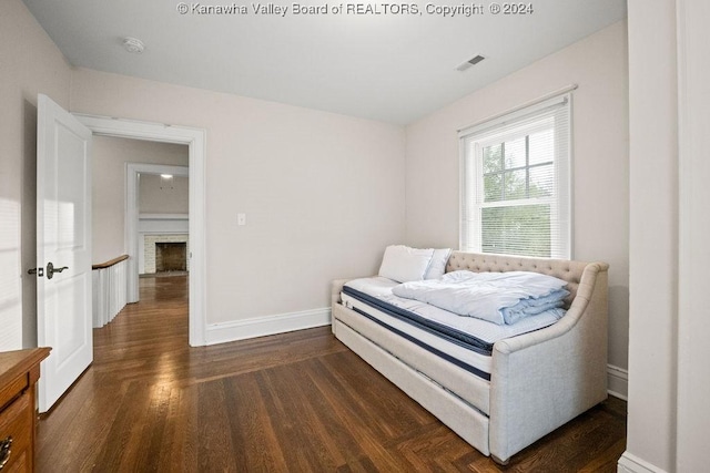 bedroom featuring dark hardwood / wood-style floors and a brick fireplace