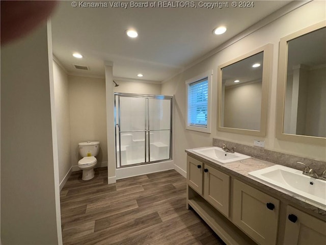 bathroom featuring hardwood / wood-style floors, toilet, a shower with door, vanity, and ornamental molding