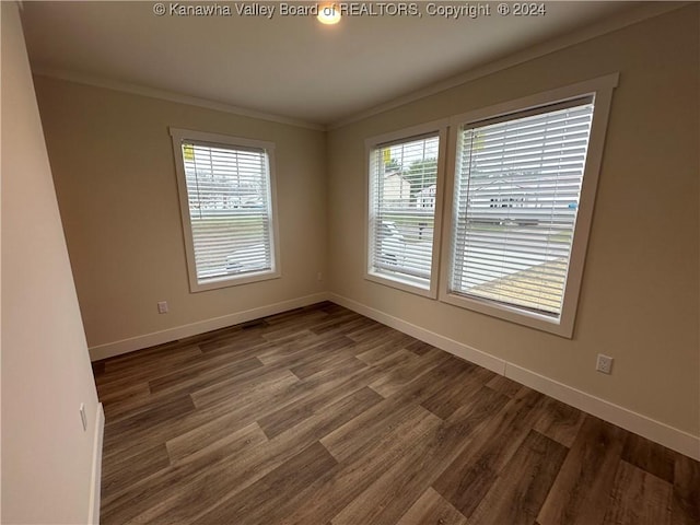 spare room with dark wood-type flooring, a healthy amount of sunlight, and ornamental molding