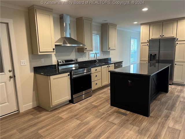 kitchen with a center island, wall chimney exhaust hood, stainless steel appliances, and light wood-type flooring