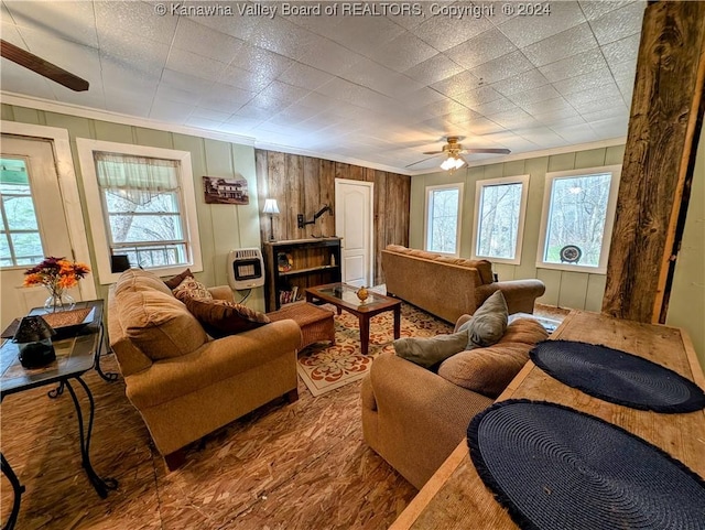 living room featuring heating unit, a wealth of natural light, ornamental molding, and ceiling fan