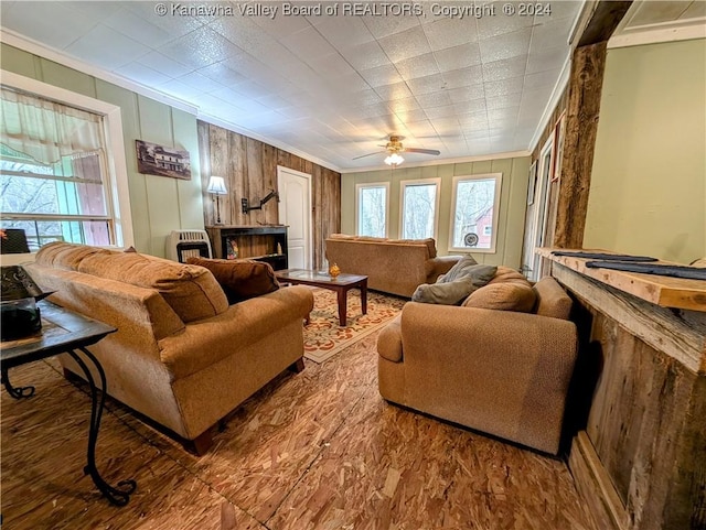 living room featuring ceiling fan, ornamental molding, and wooden walls