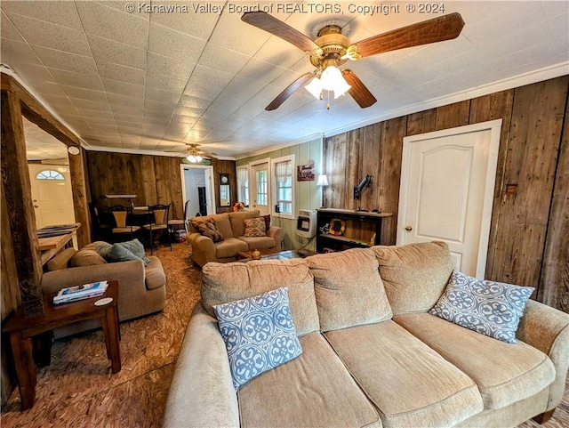 living room with wooden walls, ceiling fan, and ornamental molding