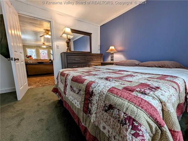 bedroom featuring ornamental molding, vaulted ceiling, and dark colored carpet