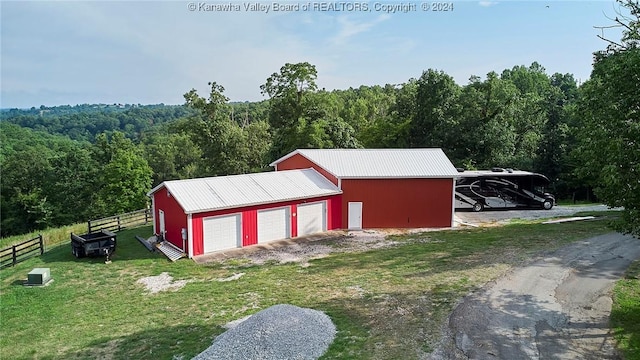 view of outdoor structure with a lawn, a carport, and a garage