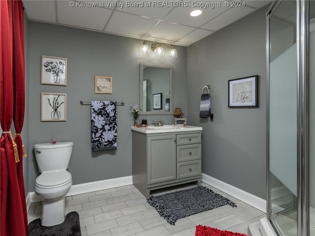 bathroom featuring a drop ceiling, tile patterned flooring, an enclosed shower, toilet, and vanity