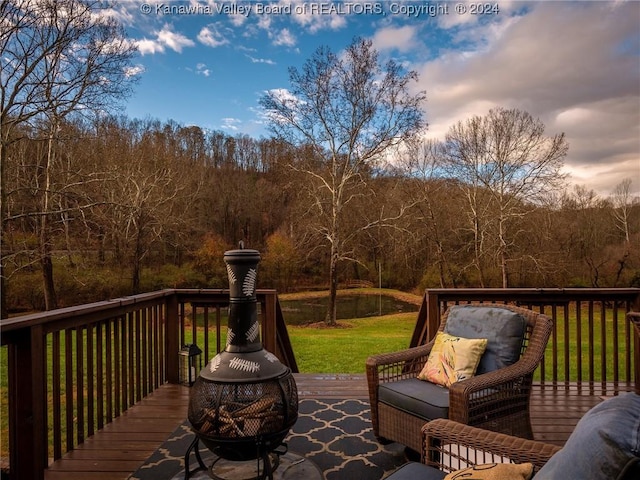 deck at dusk featuring a fire pit and a lawn