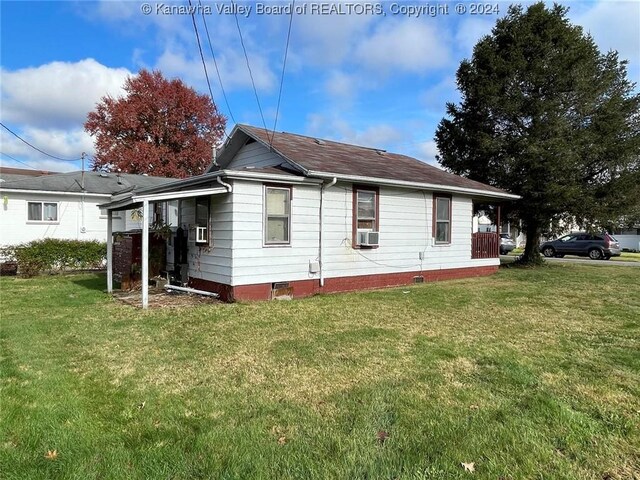 view of side of property featuring cooling unit and a yard