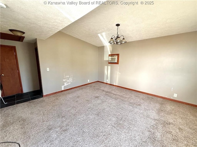 carpeted spare room with a chandelier and a textured ceiling