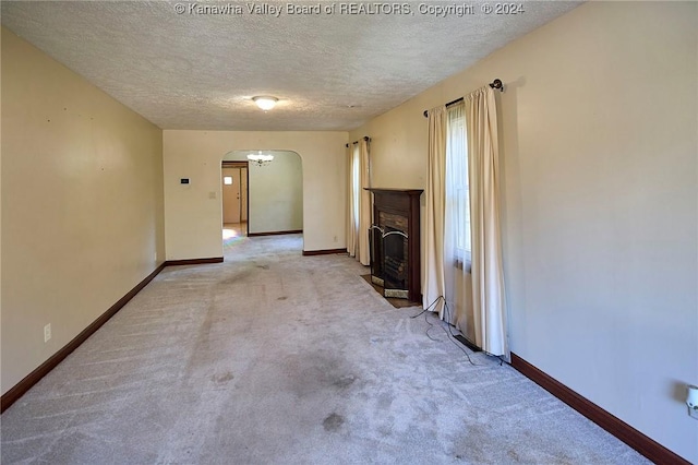 unfurnished living room with light colored carpet and a textured ceiling