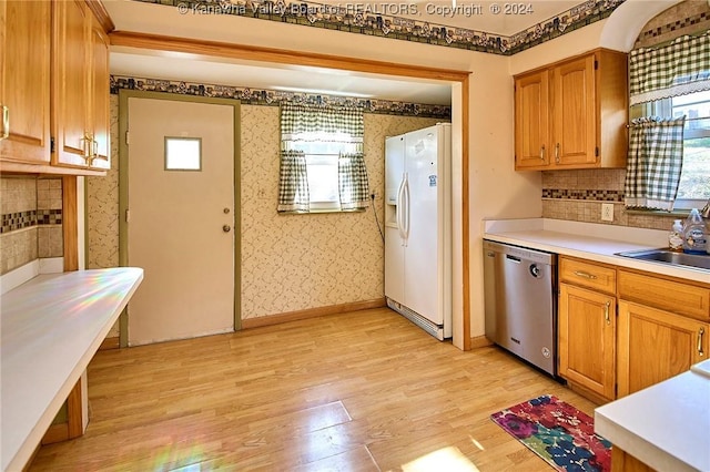 kitchen with decorative backsplash, stainless steel dishwasher, sink, light hardwood / wood-style flooring, and white fridge with ice dispenser