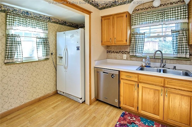 kitchen with white refrigerator with ice dispenser, sink, stainless steel dishwasher, decorative backsplash, and light hardwood / wood-style floors