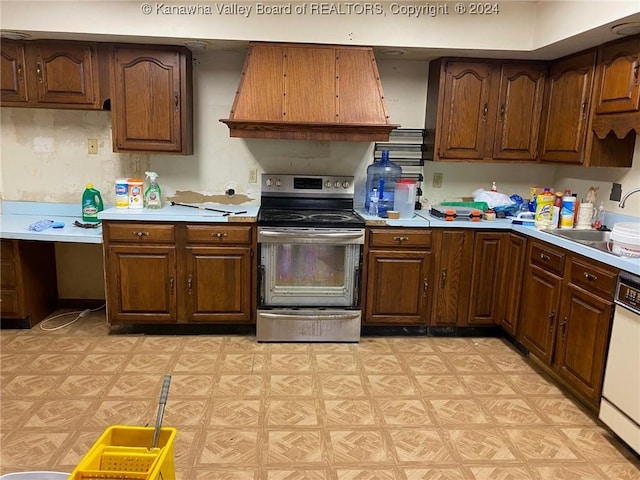 kitchen featuring premium range hood, sink, stainless steel range with electric cooktop, and white dishwasher