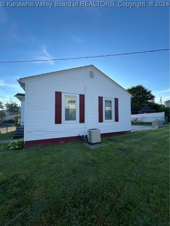 back of property featuring a yard and central AC