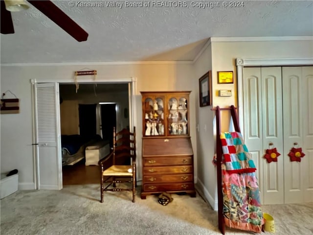 interior space with a textured ceiling, ceiling fan, carpet floors, and ornamental molding