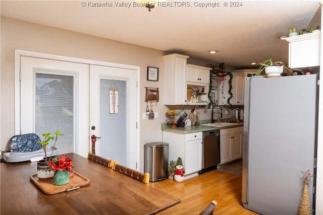 kitchen with white cabinets, sink, white refrigerator, light hardwood / wood-style flooring, and dishwasher