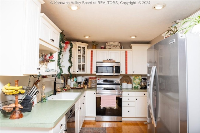 kitchen featuring light hardwood / wood-style floors, white cabinetry, sink, and appliances with stainless steel finishes