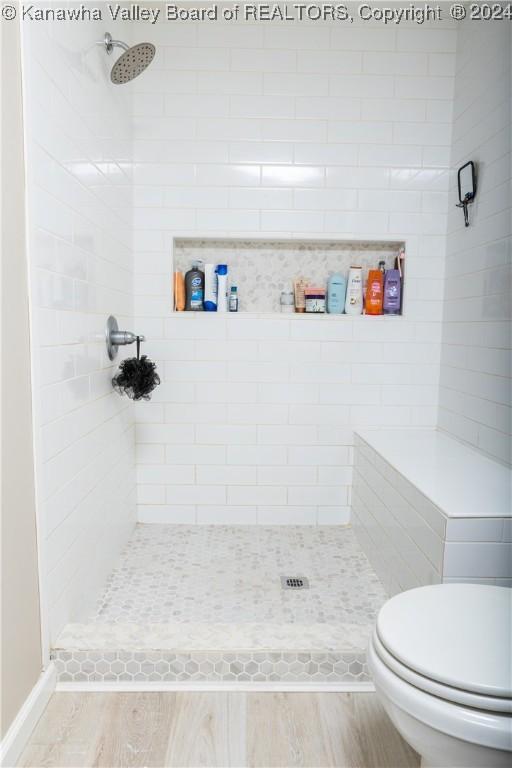 bathroom featuring hardwood / wood-style floors, toilet, and a tile shower