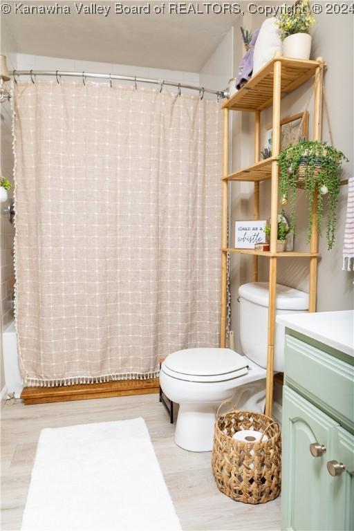 full bathroom with shower / bath combo, vanity, hardwood / wood-style flooring, and toilet