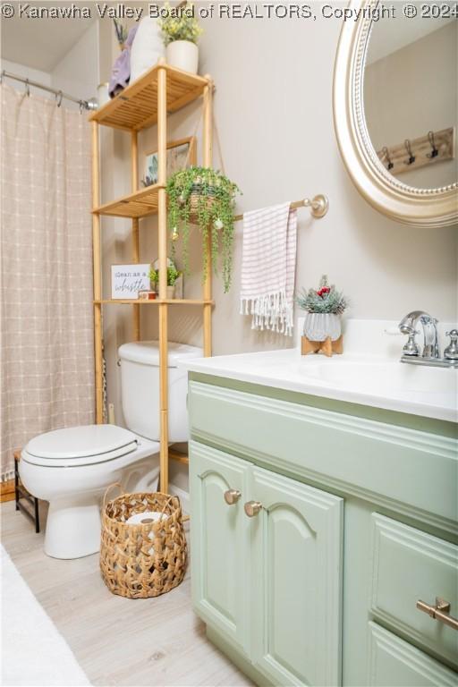 bathroom featuring hardwood / wood-style floors, vanity, toilet, and walk in shower