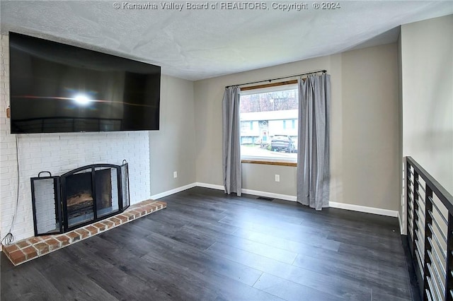 unfurnished living room with a textured ceiling, dark hardwood / wood-style floors, and a brick fireplace