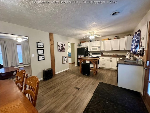 kitchen featuring sink, dark hardwood / wood-style floors, a textured ceiling, white appliances, and white cabinets