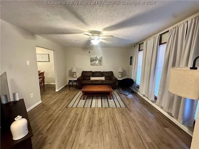 living room featuring a textured ceiling, ceiling fan, and dark wood-type flooring