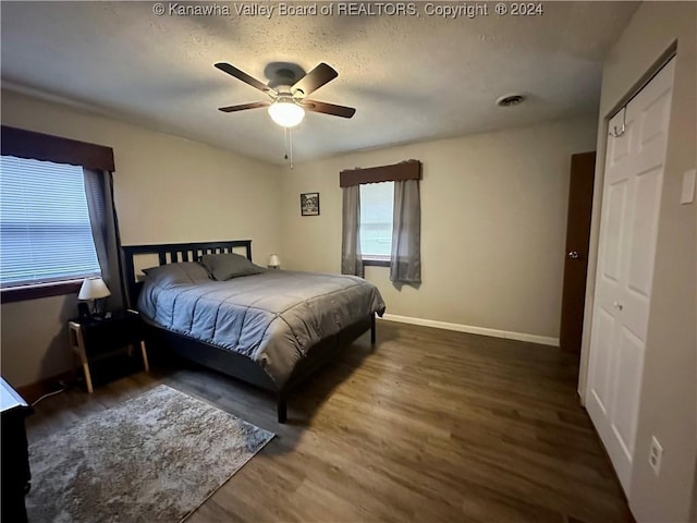bedroom with ceiling fan, dark hardwood / wood-style flooring, and a textured ceiling