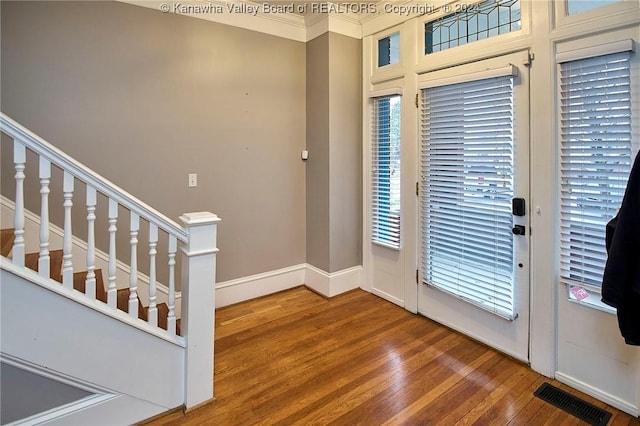 foyer with visible vents, crown molding, baseboards, stairs, and wood finished floors