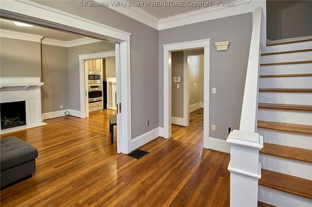 stairs featuring a fireplace with flush hearth, wood finished floors, baseboards, and ornamental molding