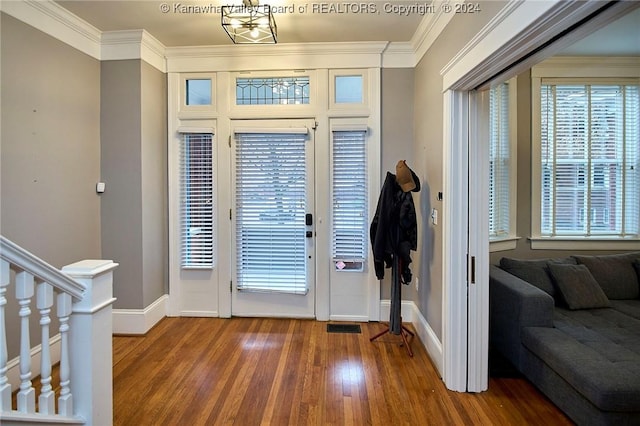 foyer entrance featuring visible vents, ornamental molding, baseboards, and wood finished floors