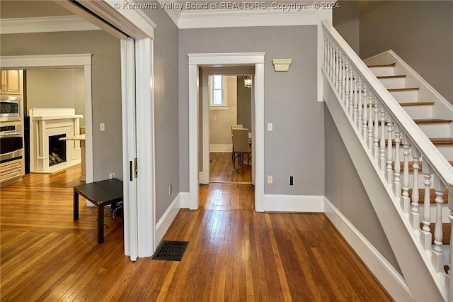 hallway featuring visible vents, stairway, crown molding, and hardwood / wood-style flooring