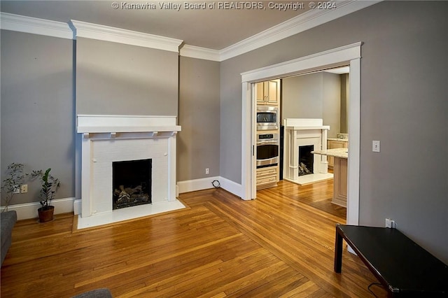 living area featuring baseboards, wood finished floors, a fireplace, and crown molding