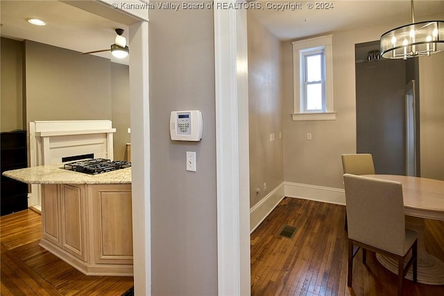 kitchen with visible vents, dark wood finished floors, baseboards, a chandelier, and light stone countertops